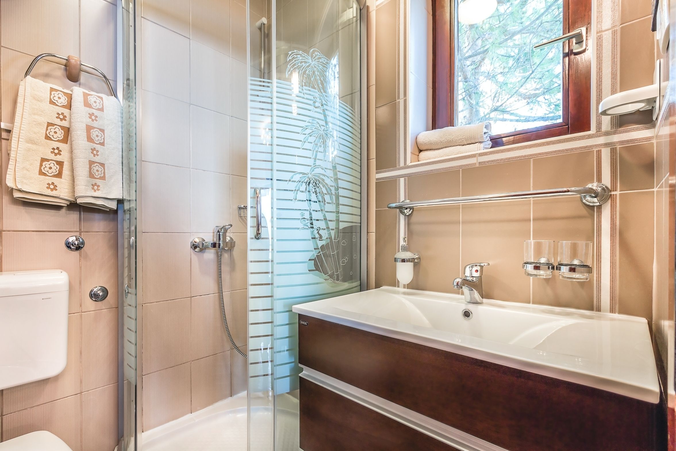 A modern bathroom with a glass-enclosed shower, a large bathtub, and a vanity with a mirror.