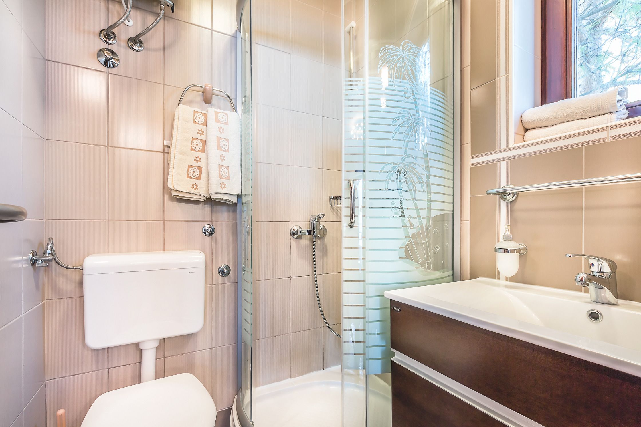 A modern bathroom with a glass shower enclosure, a toilet, and a vanity with a sink and mirror.