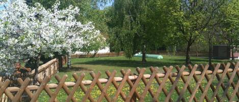 A fenced garden with blooming trees and a clear sky.