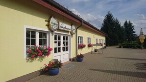 Un bâtiment sur lequel on peut lire l’inscription « Restaurant Freiberger ». Des jardinières remplies de fleurs roses sont posées sur les fenêtres.