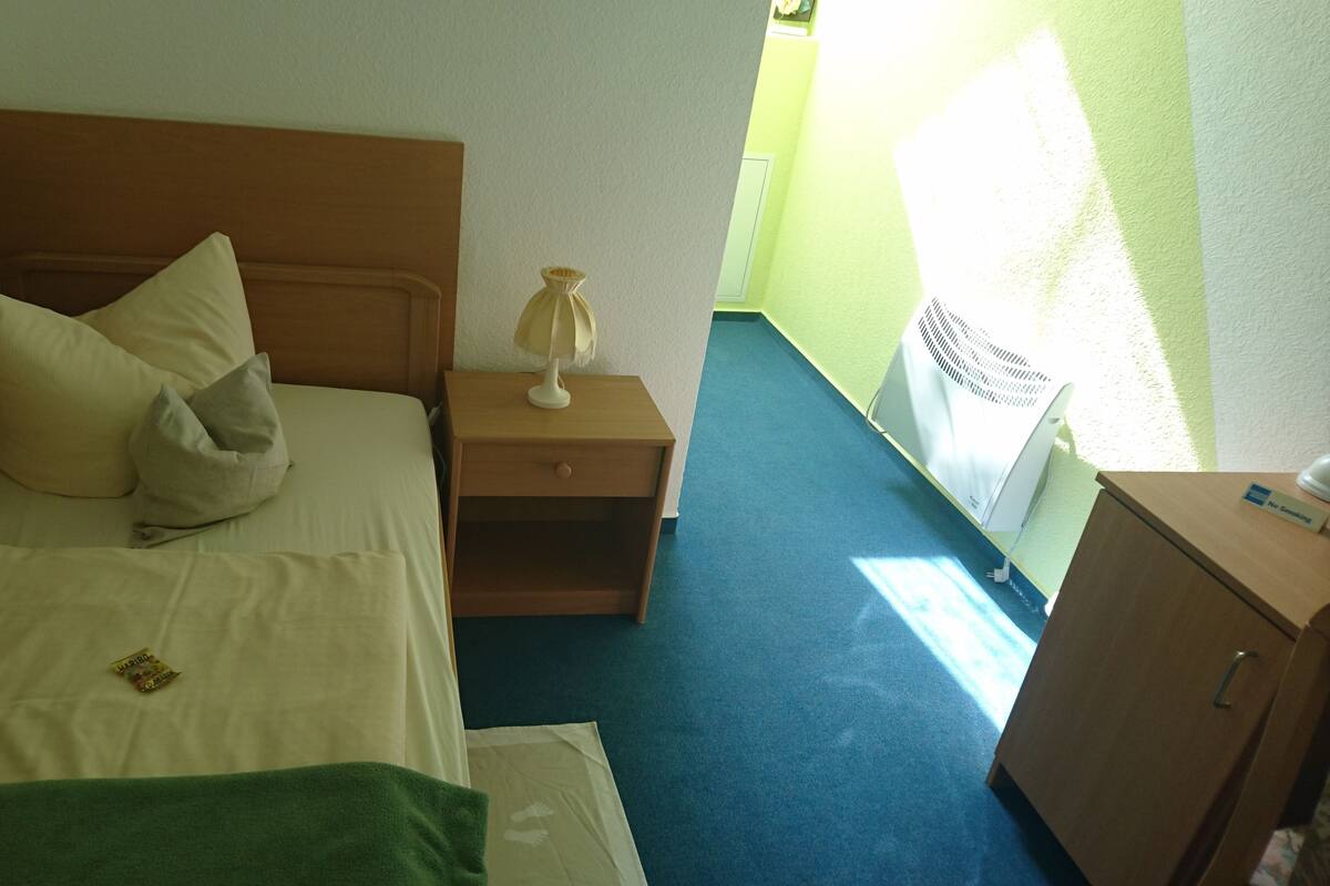 Ein Hotelzimmer mit einem Bett, einem Nachttisch mit Lampe, einem grünen Handtuch und einem Schrank.