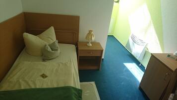 Quarto de hotel com cama, mesa de cabeceira com abajur, toalha verde e armário.