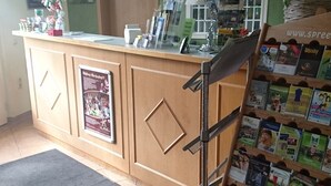 Un espace d’accueil avec un comptoir en bois, un tapis noir et un présentoir à magazines.