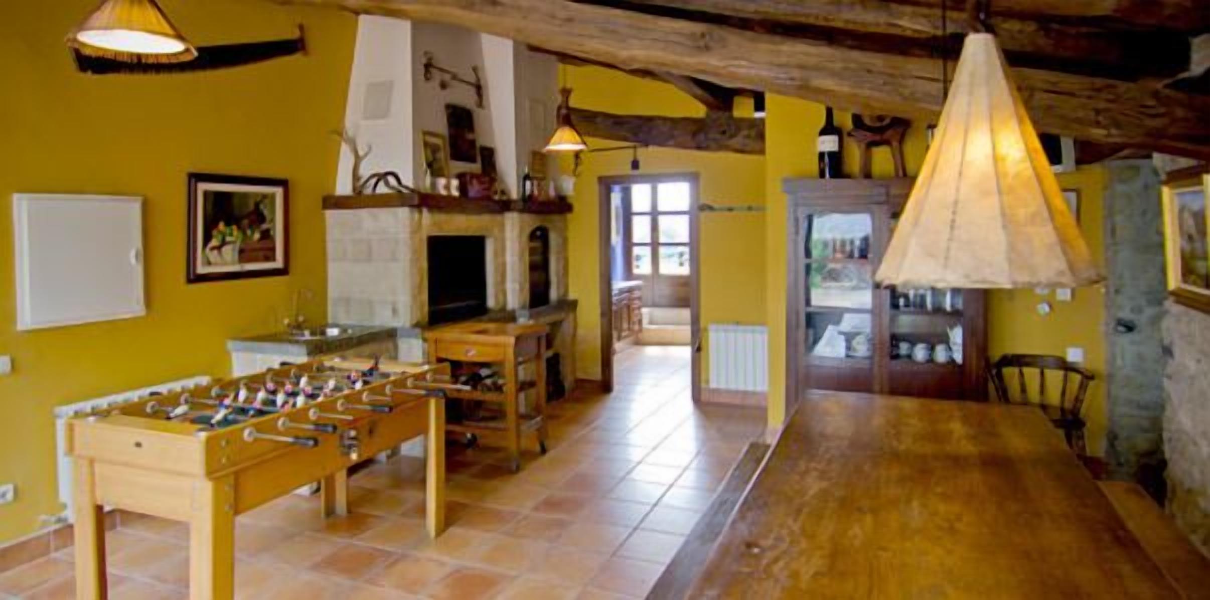 A cozy room with a foosball table, wooden furniture, and a stone wall.