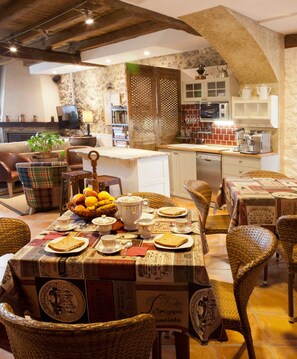 Un comedor acogedor con una pared de piedra rústica, una cocina al fondo y una mesa lista para comer.