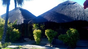 A building with thatched roofs, a paved pathway, and green shrubs. - Northgate Lodge (Nata)