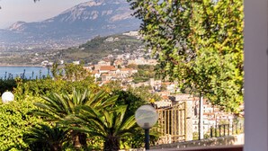 A balcony with a view of a coastal town, a table with a hat, and a lamp post. - B&B Belvedere (Agropoli)
