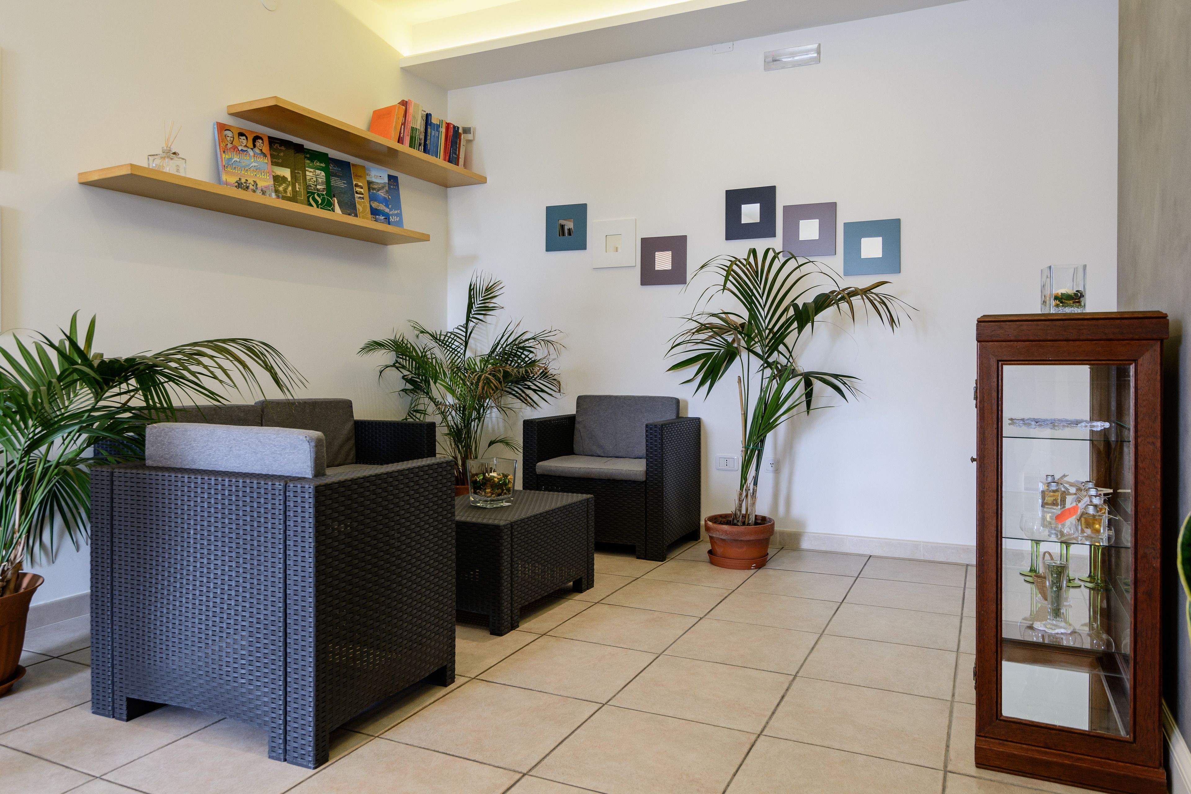 Un salon avec des meubles en osier, une table basse en verre et des plantes en pot.