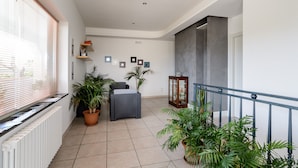 A spacious balcony with potted plants, a wicker chair, and a glass cabinet. - B&B Belvedere (Agropoli)