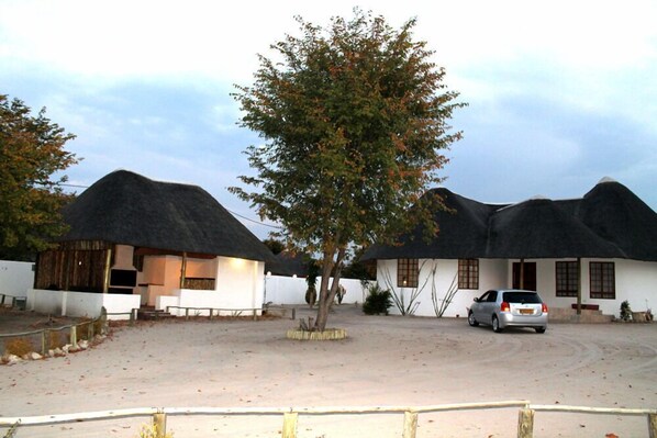 A traditional thatched-roof building with a car parked in front.