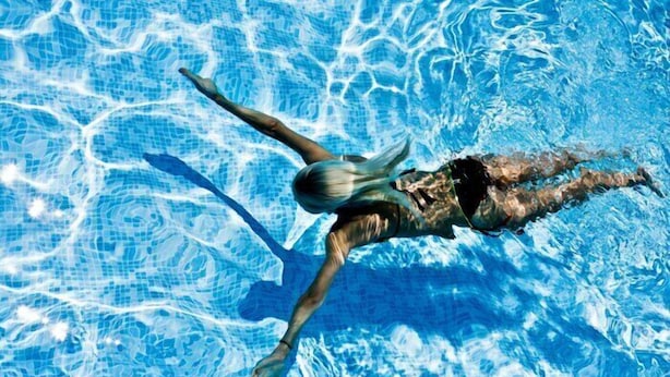 Eine Person schwimmt in einem Pool mit klarem, blauem Wasser.