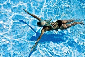 Eine Person schwimmt in einem Pool mit klarem, blauem Wasser.