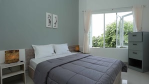 Ein Schlafzimmer mit Bett, Nachttischen, einem Kleiderschrank und einem Fenster mit Vorhängen.