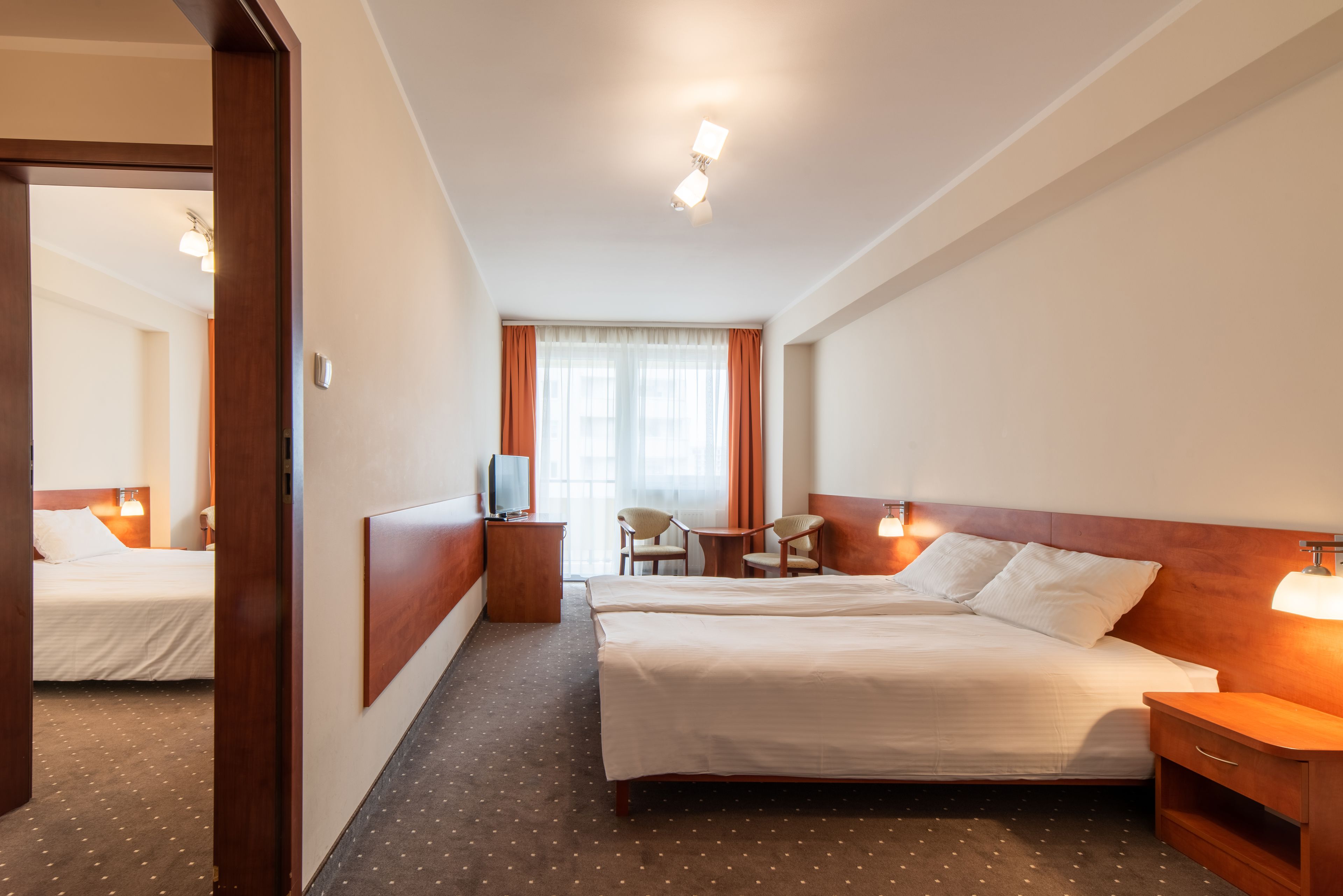 Habitación de hotel con una cama grande, un escritorio, una silla y un televisor.