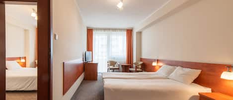 A hotel room with a large bed, a desk, a chair, and a television.