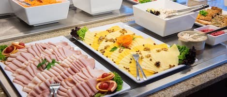 A buffet with various food options including sliced meats, cheeses, and salads.