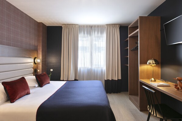 Una habitación de hotel moderna con una cama grande, un escritorio y un televisor.
