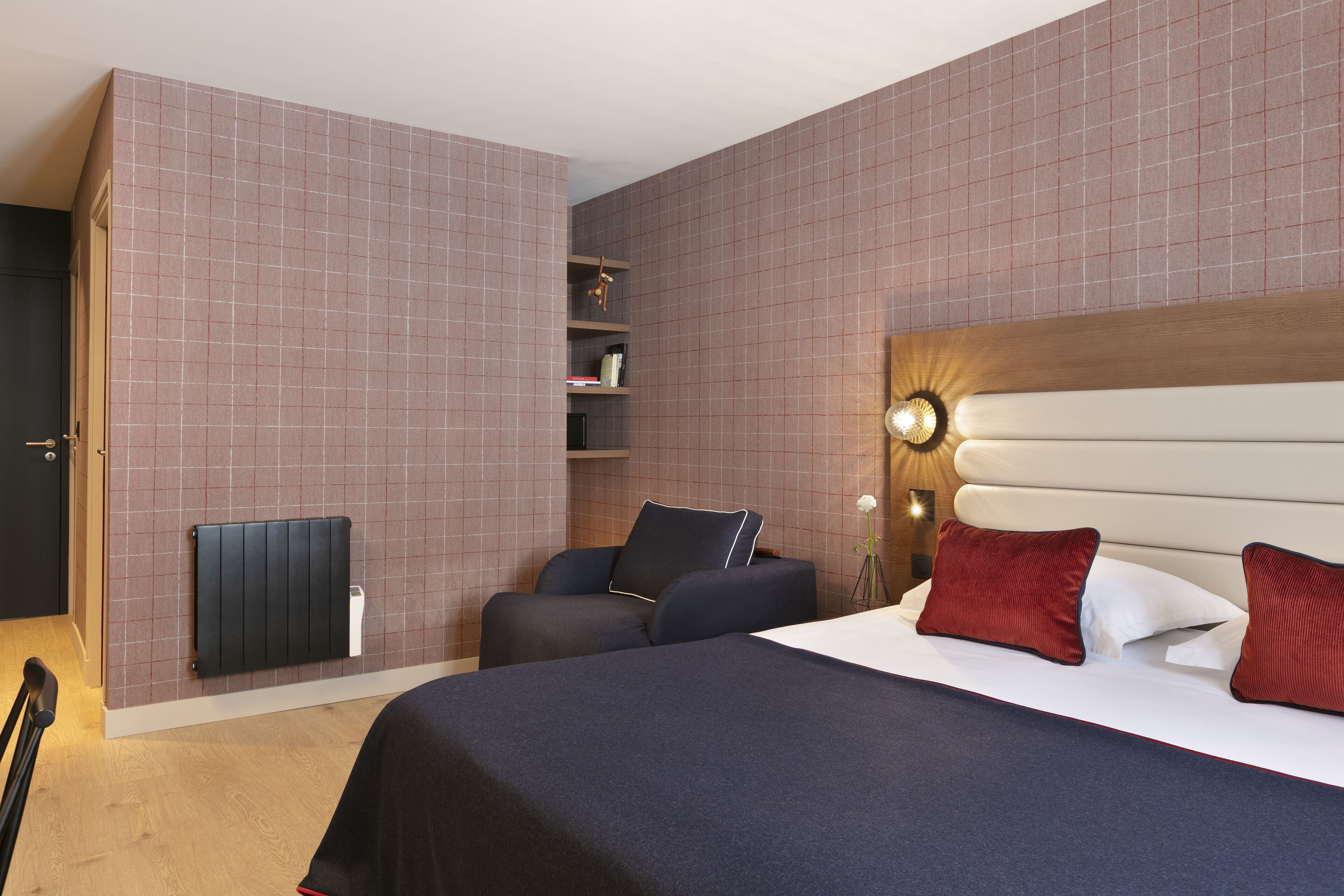 Une chambre d’hôtel avec un lit, une chaise, une table de chevet, une lampe et un radiateur.