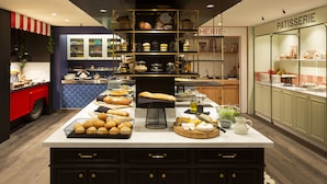 A bakery display with various breads and pastries, a coffee station, and a patisserie section.