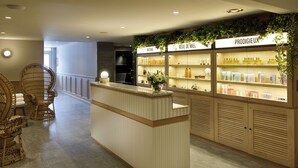 A reception area with a wooden reception desk, wicker chairs, and shelves displaying products.
