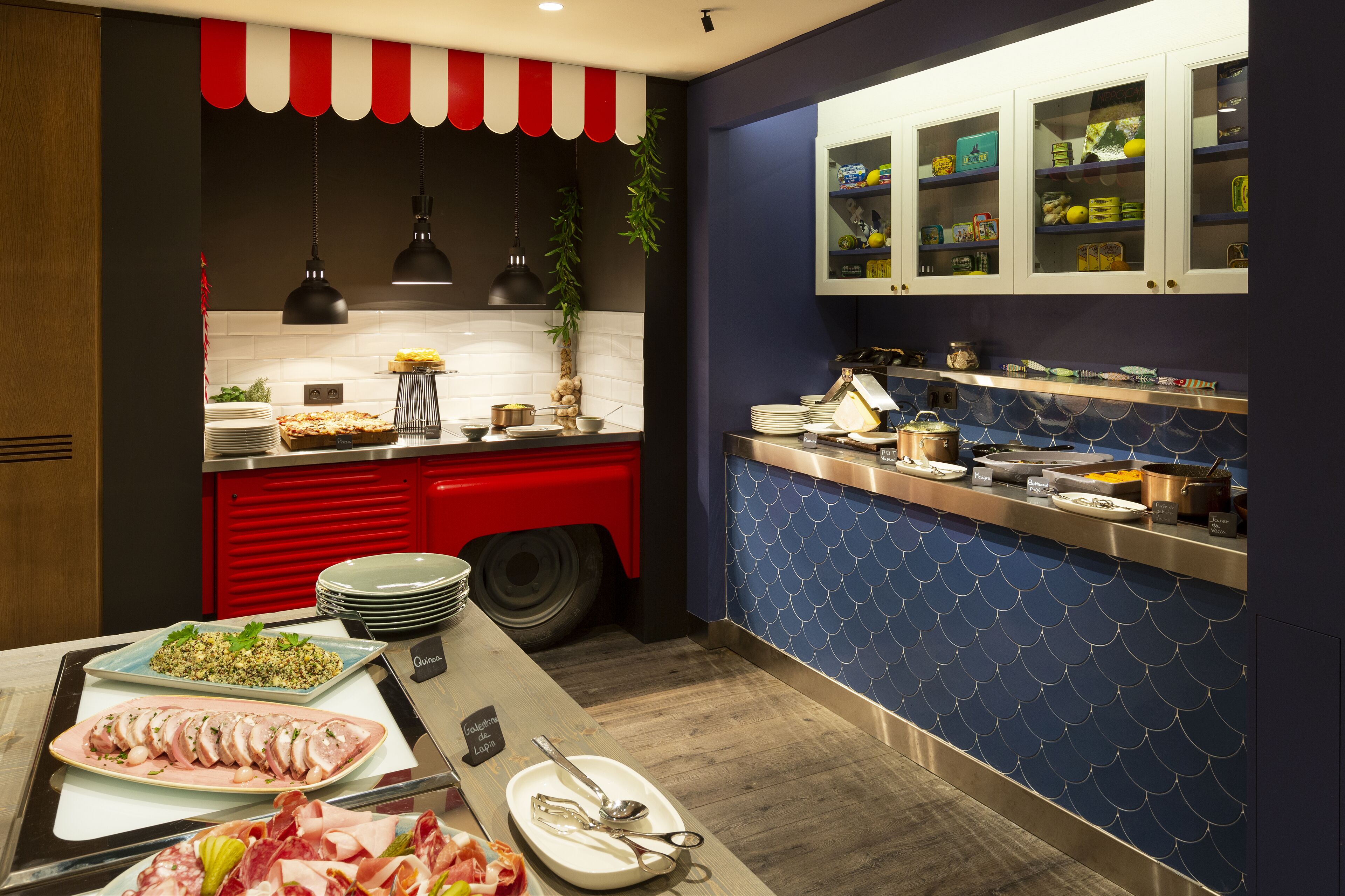 A modern kitchen with a red and white striped awning, a blue tiled backsplash, and a variety of food items displayed on the counter.