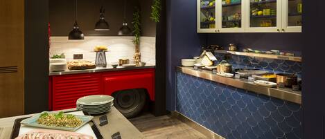 A modern kitchen with a red and white striped awning, a blue tiled backsplash, and a variety of food items displayed on the counter.