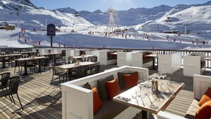 A restaurant with outdoor seating overlooking a snowy mountain landscape.