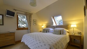 A bedroom with a large bed, two bedside tables, a TV, and a window with curtains. - Brae House Bed & Breakfast (Aberfeldy)