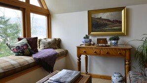 A cozy room with a large window, a wooden desk, a cushioned bench, and a framed painting. - Brae House Bed & Breakfast (Aberfeldy)