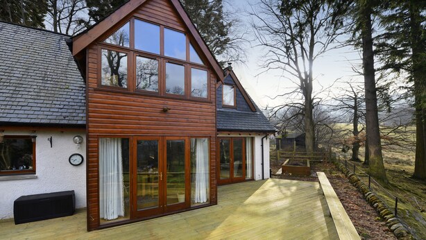 A two-story wooden house with large windows and a deck. - Brae House Bed & Breakfast (Aberfeldy)