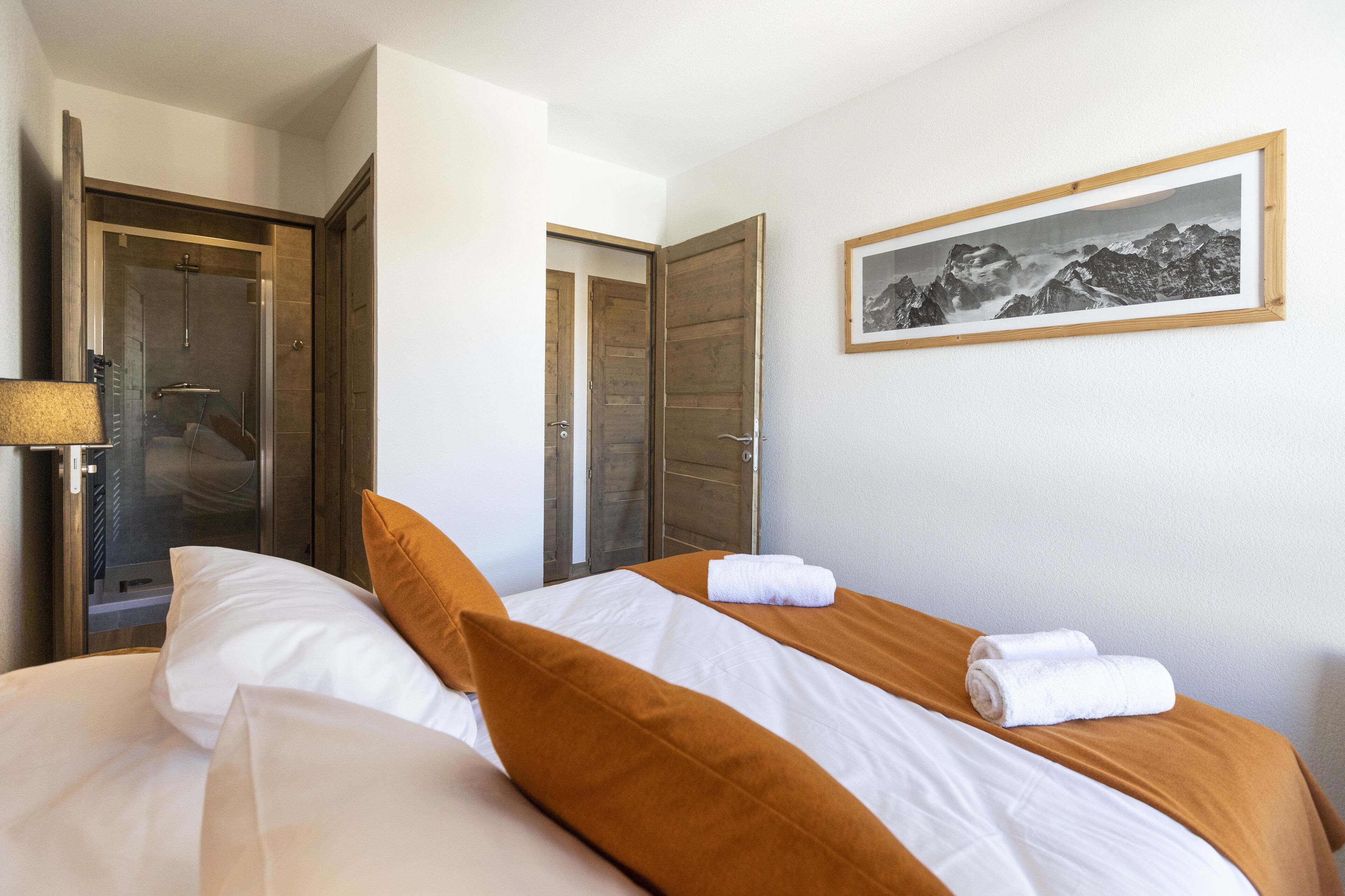 A hotel room with a bed, a shower, and a framed picture on the wall.