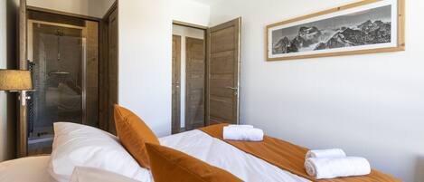A hotel room with a bed, a shower, and a framed picture on the wall.