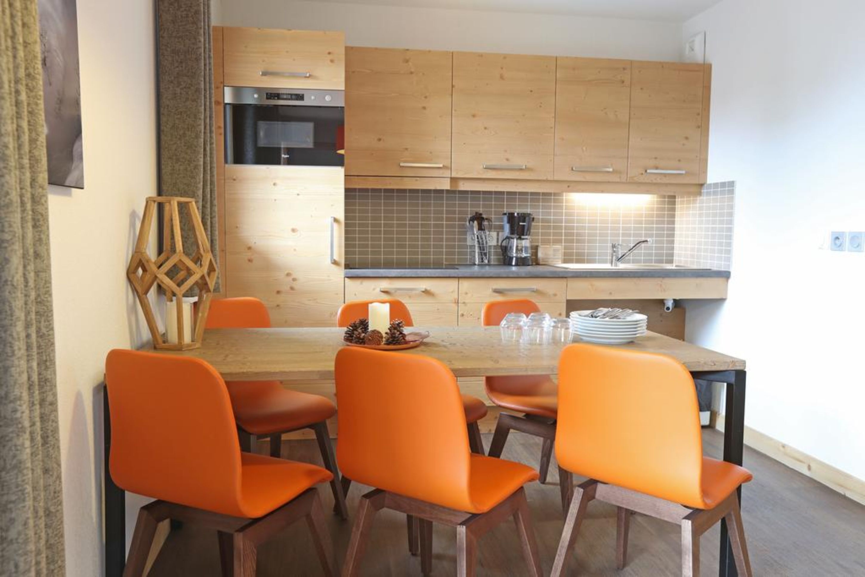 A modern kitchen with wooden cabinets, a built-in oven, and a tiled backsplash.