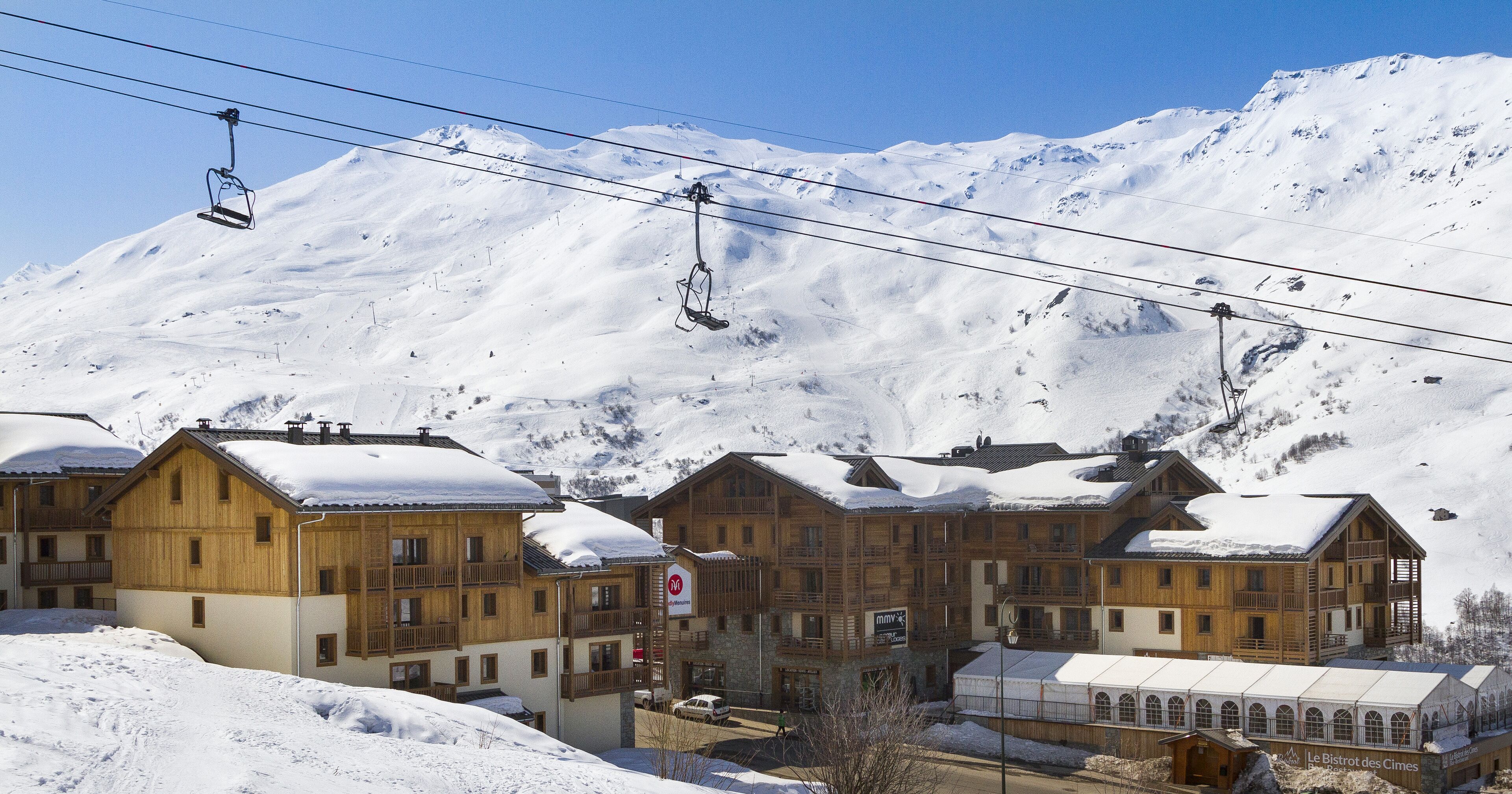 Une montagne enneigée, avec un télésiège et des bâtiments en bois dotés de balcons.