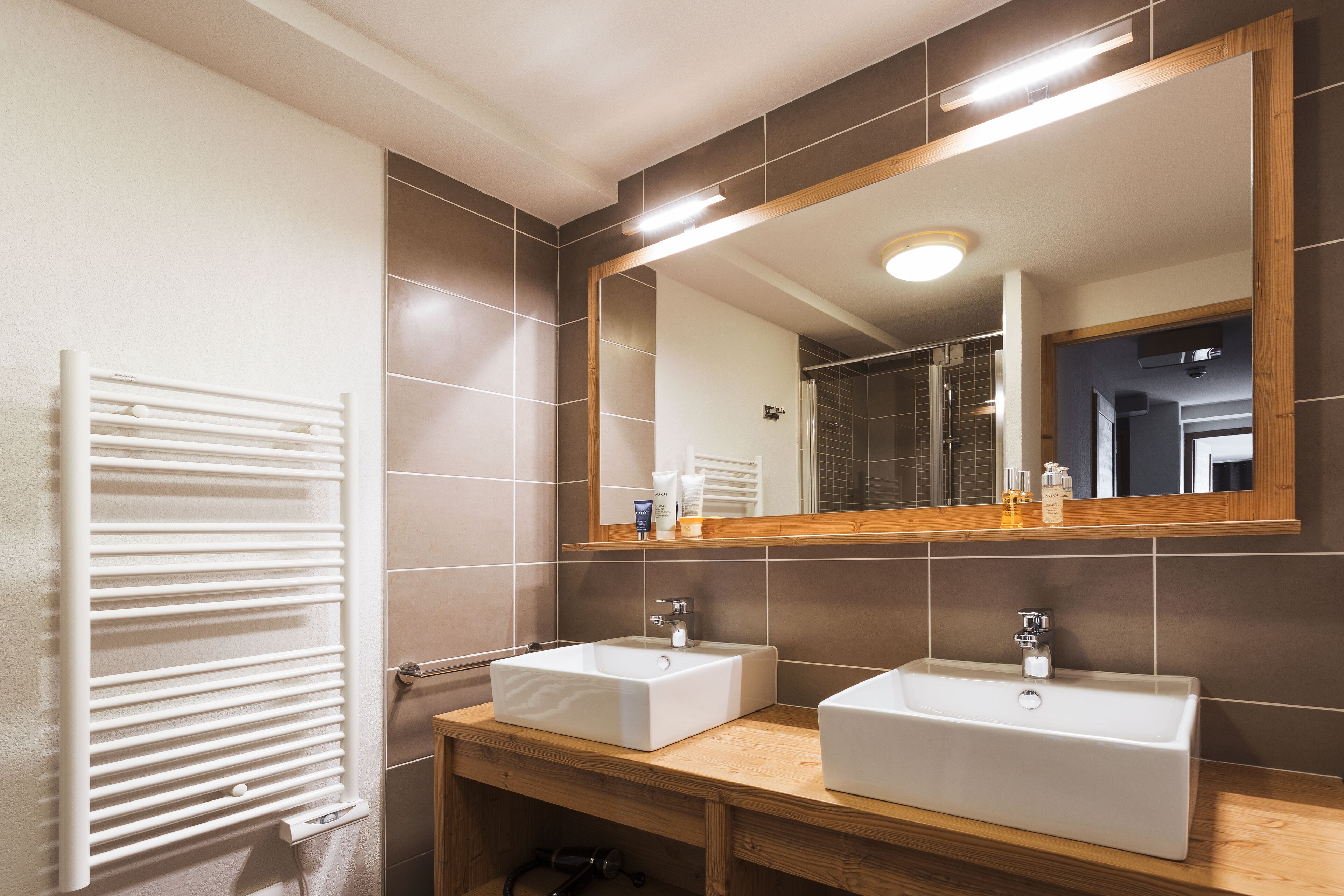A bathroom with two sinks, a mirror, and a towel rack.