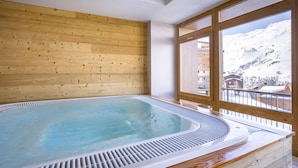 Un jacuzzi en una habitación con paredes de madera y un ventanal grande.