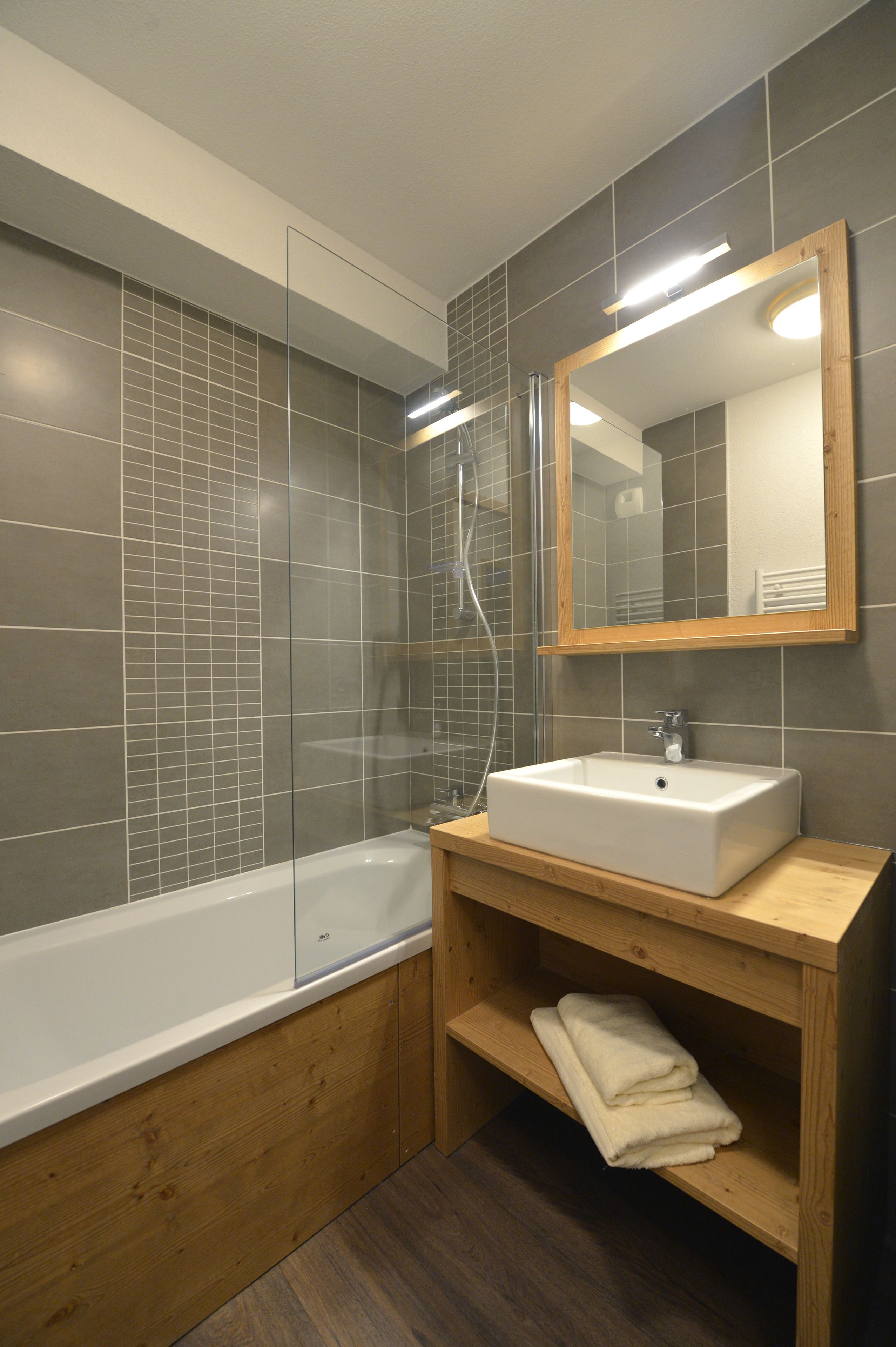 A modern bathroom with a bathtub, a sink, and a mirror.