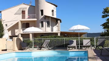 Una piscina al aire libre de temporada, sombrillas