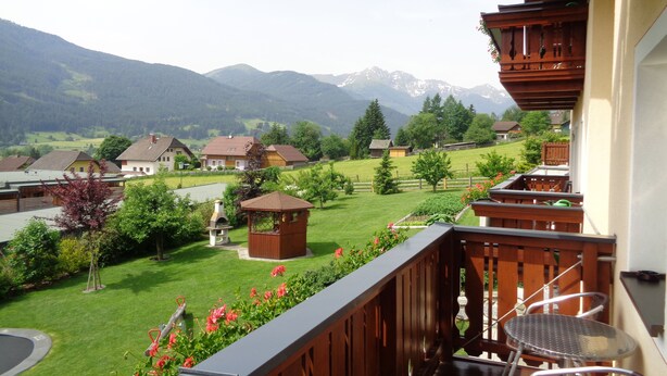 Un balcón con vistas a un paisaje verde, casas y montañas.