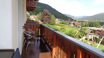 Ein Balkon mit Holzbalkon, einem Tisch und zwei Stühlen.