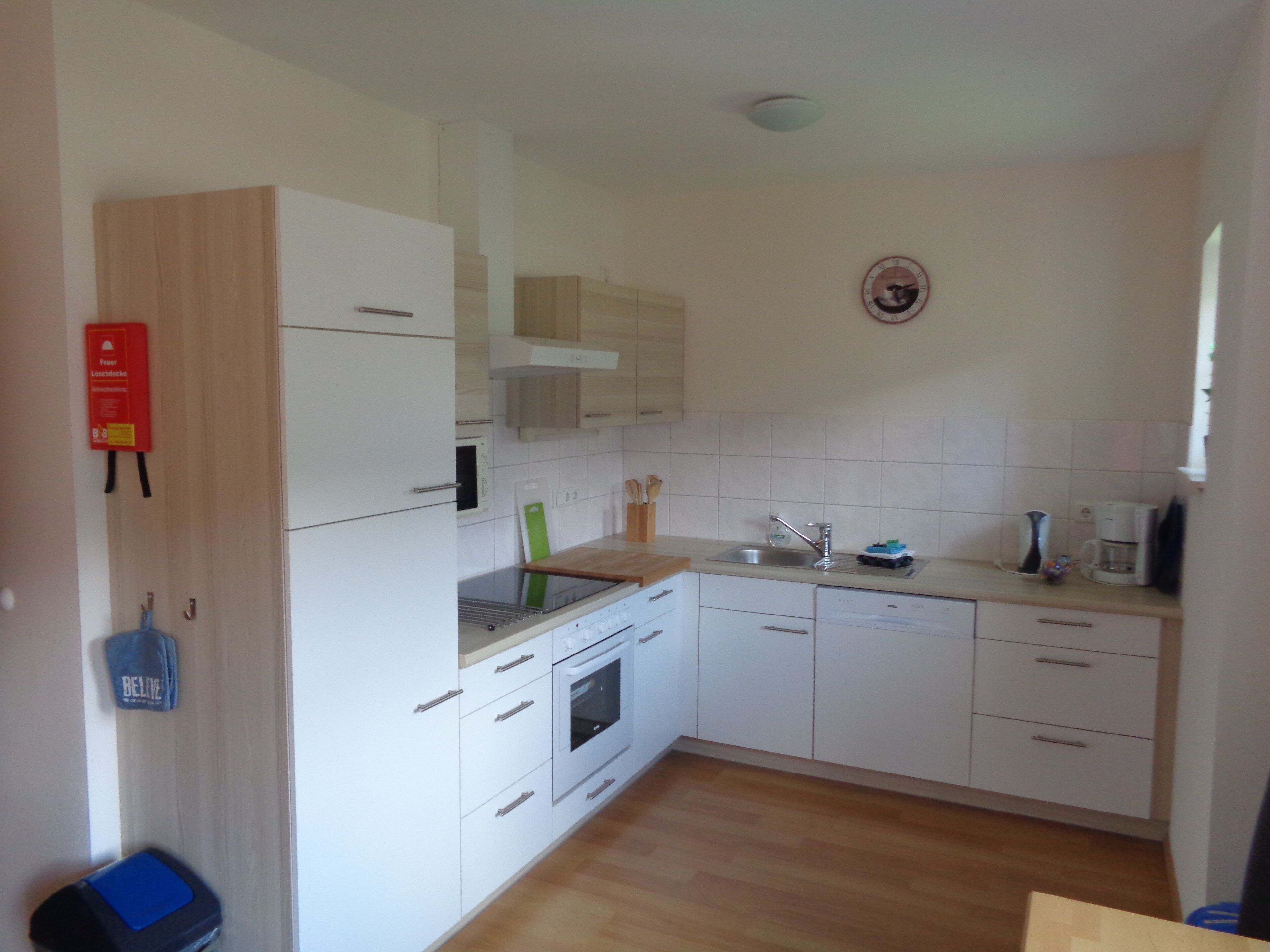 A kitchen with white cabinets, a stainless steel sink, and a built-in oven.