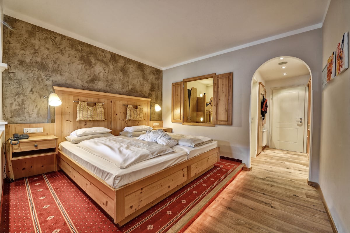A bedroom with a wooden bed, a nightstand, a lamp, and a mirror.