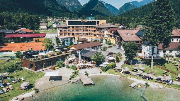 An aerial view of a resort with a pool, outdoor seating, and a mountain backdrop. - Post Family Resort (Unken)
