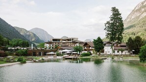 A lakeside hotel with a pool, outdoor seating, and mountain views. - Post Family Resort (Unken)