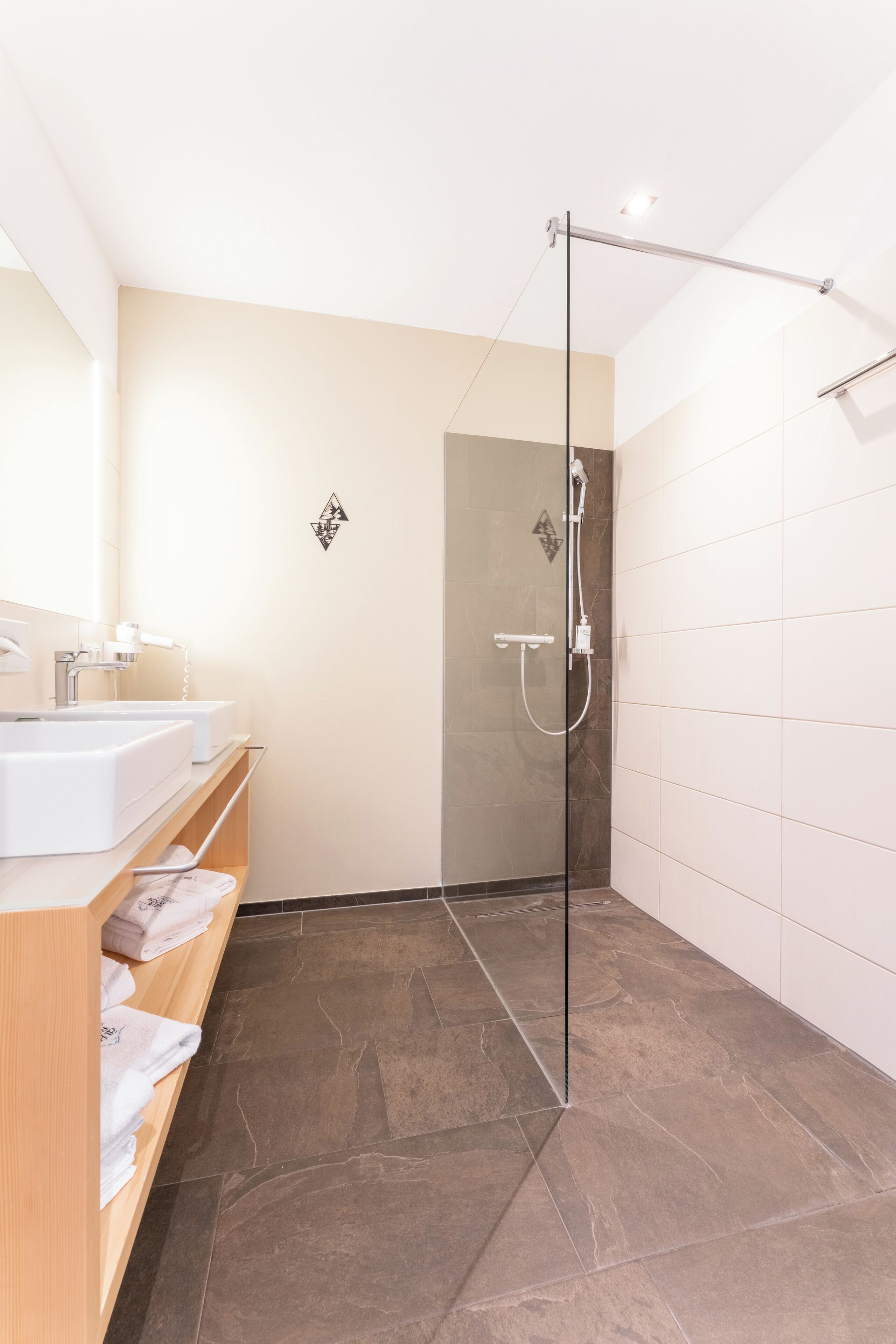 A modern bathroom with a glass shower enclosure, a vanity with two sinks, and a towel rack.
