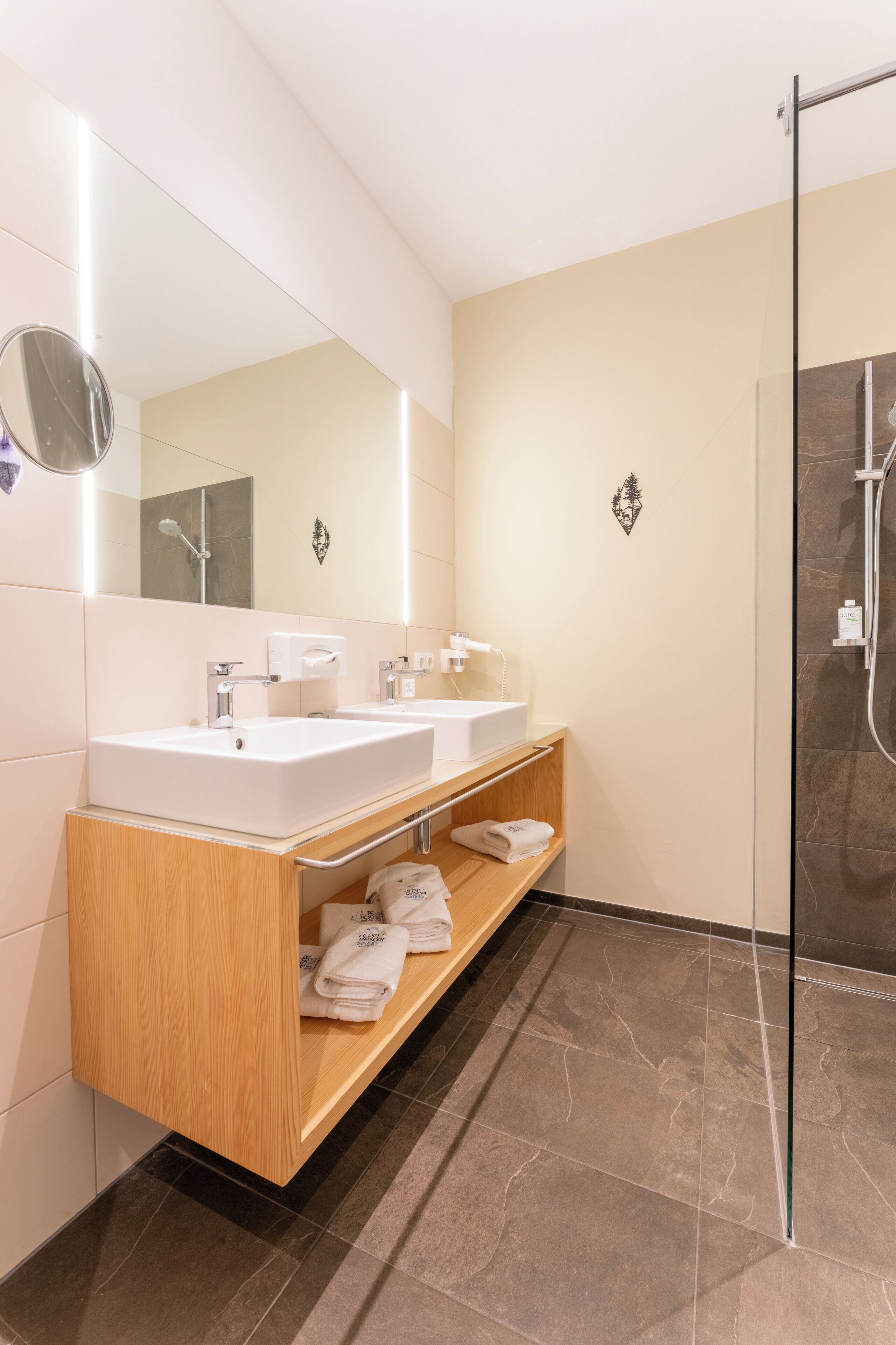 Un baño moderno con dos lavamanos, un espejo y cabina de ducha de vidrio.