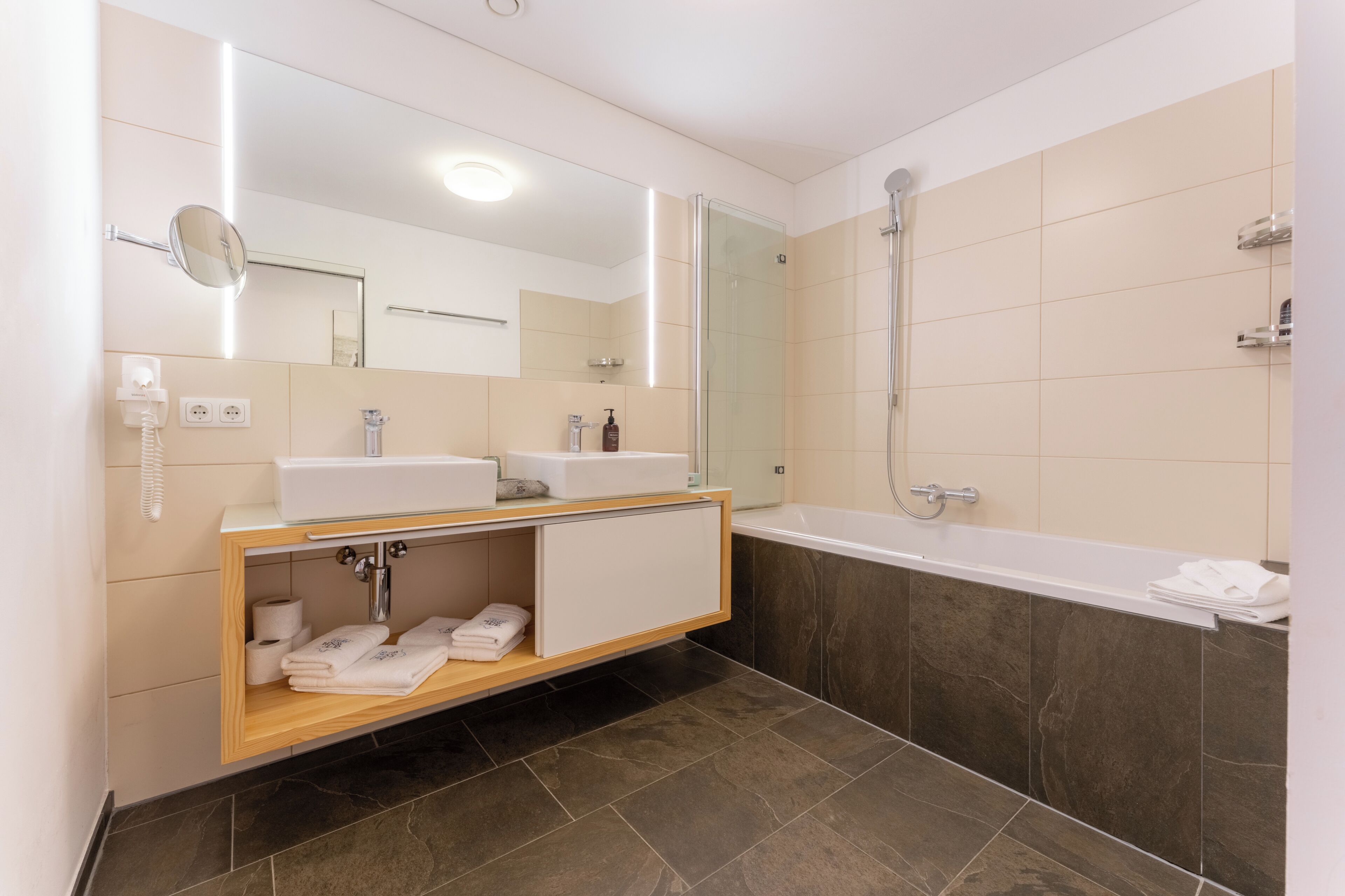 A modern bathroom with a vanity, a mirror, a shower, and a bathtub.