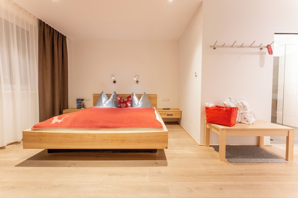A modern bedroom with a wooden bed, a bedside table, a red basket, and a wooden bench.