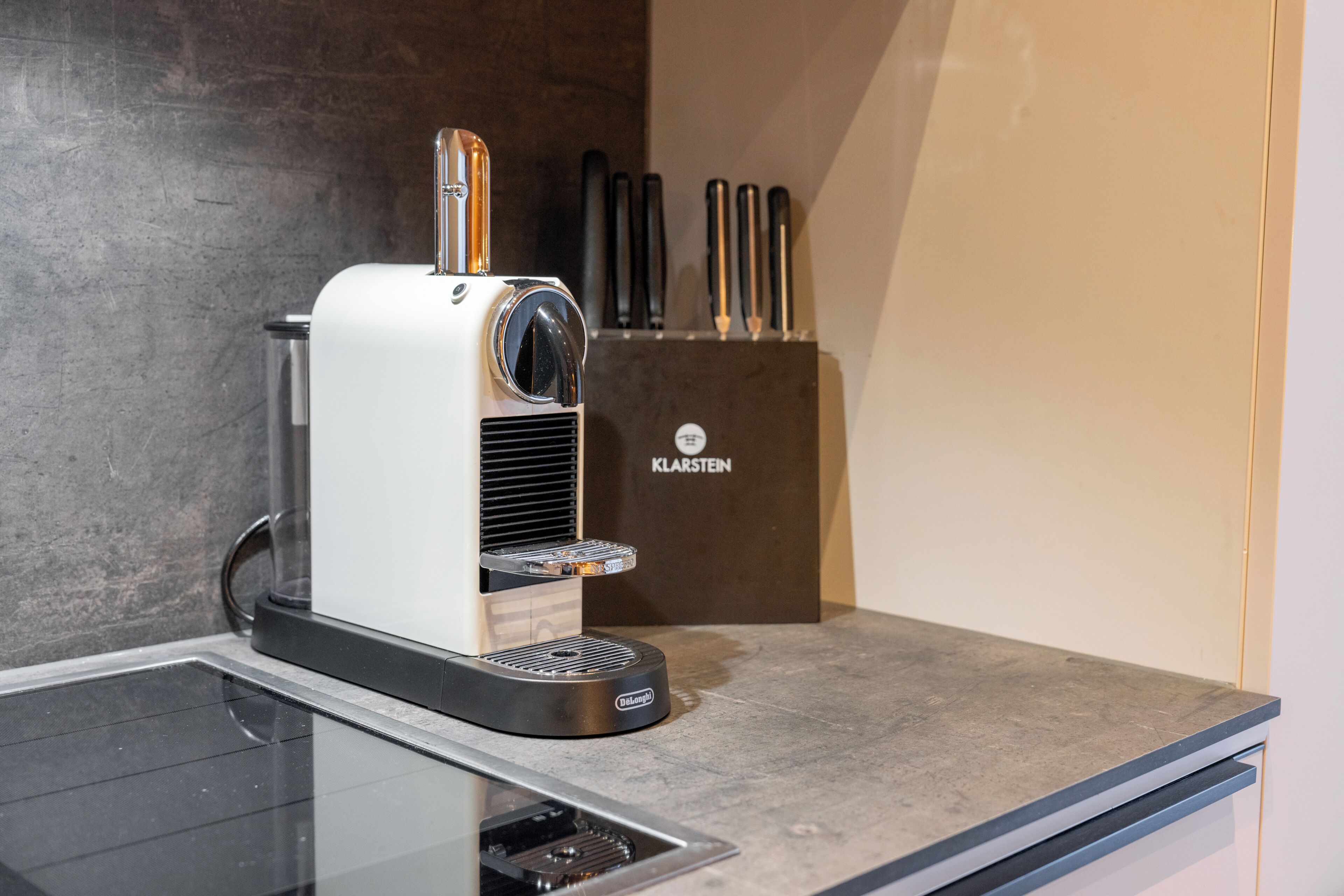 A coffee machine on a kitchen counter with a knife block in the background.
