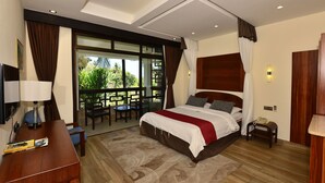 A modern bedroom with a large bed, a desk, and a balcony with outdoor seating. - Baobab Holiday Resort (Mombasa)